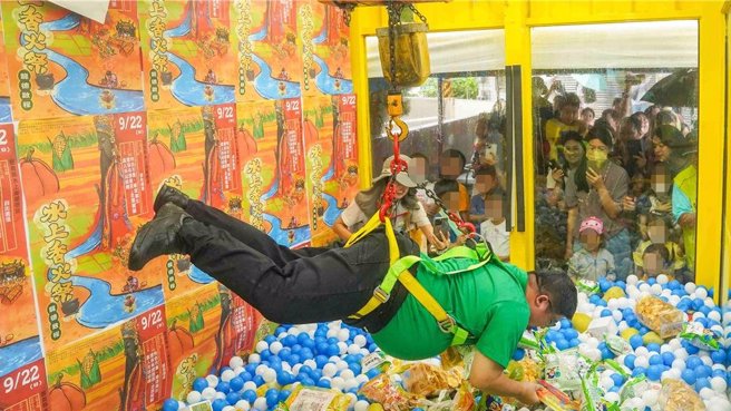 體重約百公斤立委蔡易餘上陣親自示範，吸引大批民眾圍觀，蔡易餘還自嘲「好像吊豬肉」，稱真人夾娃娃機耐重測試成功。（蔡易餘服務處提供／呂妍庭嘉義傳真）