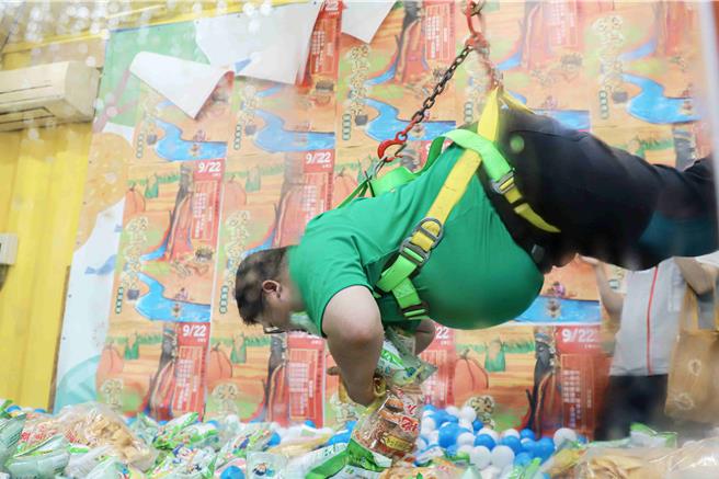 體重約百公斤立委蔡易餘上陣親自示範，吸引大批民眾圍觀，蔡易餘還自嘲「好像吊豬肉」，稱真人夾娃娃機耐重測試成功。（呂妍庭攝）