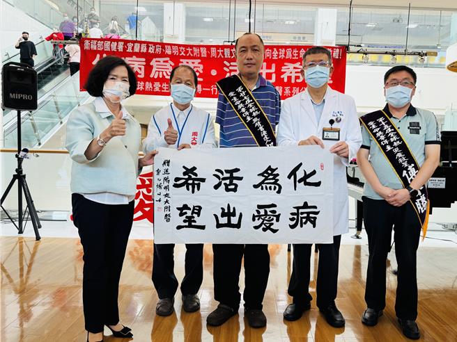 中國大陸無臂書法達人郭以博（中）撰寫書法贈與陽明交通大學附設醫院。（吳佩蓉攝）