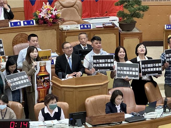 新北市議會民進黨團總召張維倩帶領全體民進黨議員上台向侯友宜送上「蠻牛」，議員們高喊「地方建設不能等、中央預算要審查」，希望侯能打起精神好好做事。（高鈞麟攝）