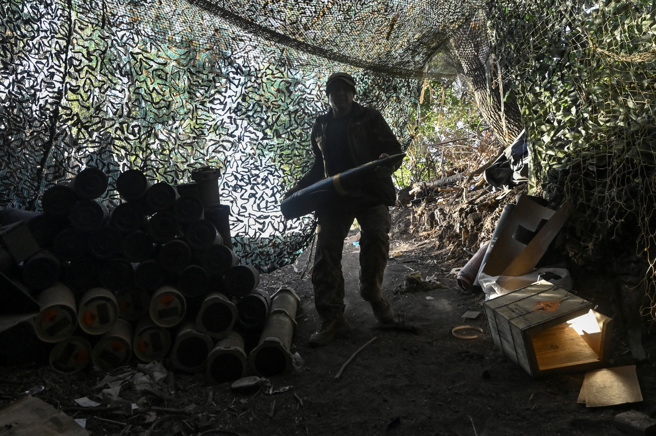 2024年9月24日，烏克蘭哈爾科夫地區，一名烏克蘭軍人扛155 毫米砲彈準備向俄軍開火。（路透社）