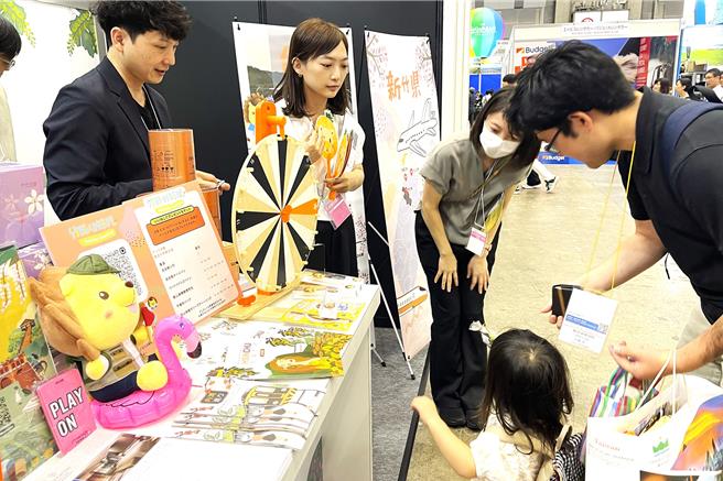 新竹縣26日在日本展旅台灣館設展攤，只要追蹤「竹縣好好玩」IG，就可以玩命運轉盤1次，即可獲吉祥物皮皮獅周邊商品，吸引不少日本親子參與。（新竹縣政府提供／羅浚濱新竹傳真）