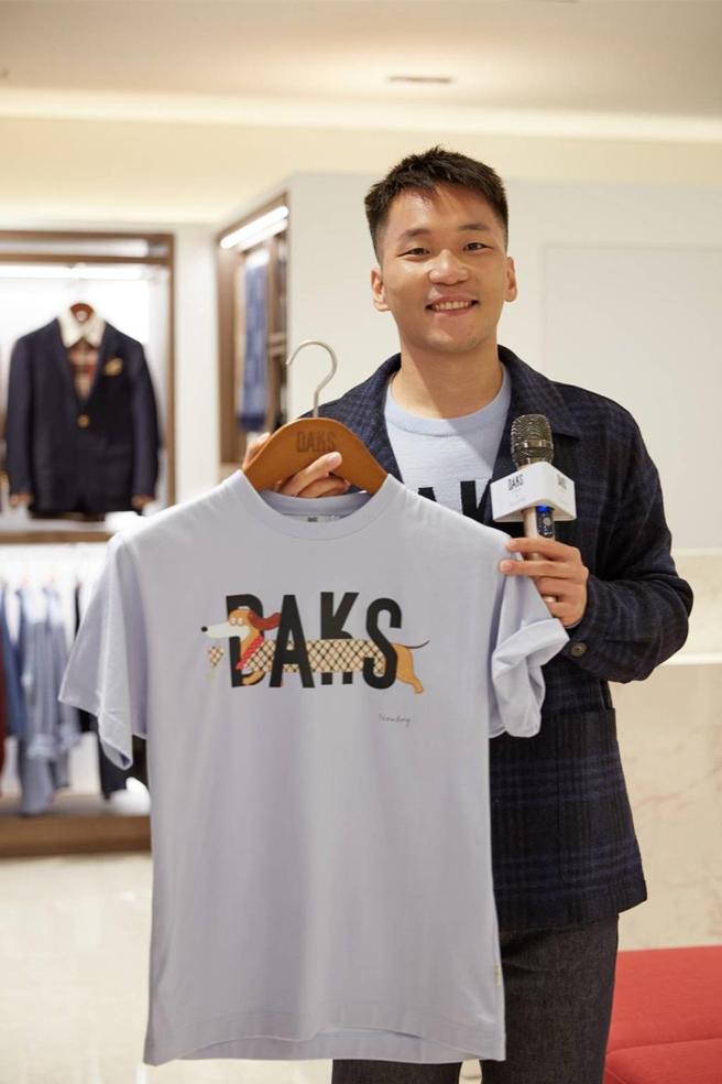 李洋拿著為慶祝DAKS 130周年，今年春夏與華裔時尚插畫家Slowboy推出合作系列商品，臘腸狗「Max」可愛的模樣，深受消費者喜愛。圖／業者提供
