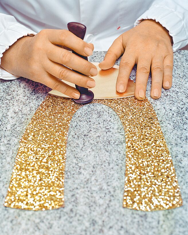 製作一雙芭蕾舞鞋需要經過兩百多道工序，圖為鞋面的鞋頭摺疊工序，這個步驟主要是為壓平接縫。工匠正在將閃粉鞋面與金屬色納帕軟皮鞋頭縫合起來。 （FERRAGAMO提供）