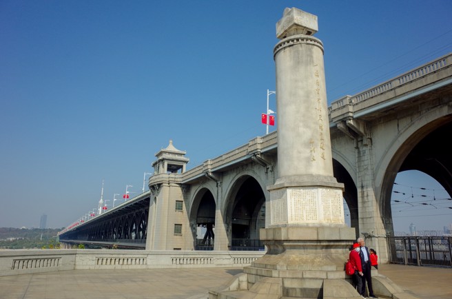 图为有「万里长江第一桥」之称的武汉长江大桥通车65周年纪念日时，市民在纪念碑前合影。  该桥于1955年9月1日动工兴建，1957年10月15日建成通车，全桥总长1670米。（资料照／ 中新社）
