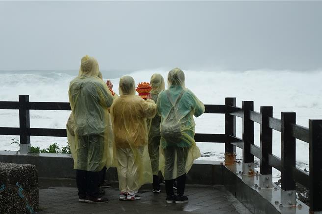 來自台中的7位修行人，在船帆石海邊手捧紙蓮花為台灣祈福。（羅琦文攝）