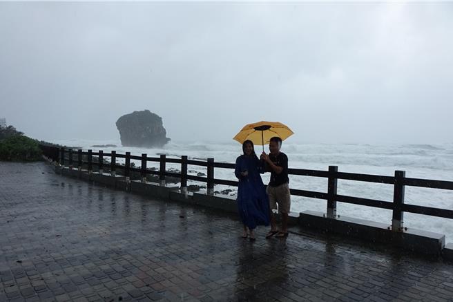 來自香港的一對夫妻在船帆石海邊拍照。（羅琦文攝）