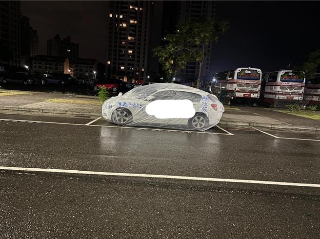 美术馆区路边停放1辆汽车被套上「全车防水袋」，相当醒目，上头写上电话，疑似是业者为打广告所为。（商姓网友提供）