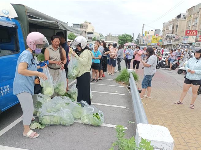 山陀兒颱風來襲，雲林縣農民搶收高麗菜，2日在北港鎮菜市場便宜賣，1顆只要80元，約為市場價格的一半，吸引近百名民眾排隊搶購。（張朝欣攝）