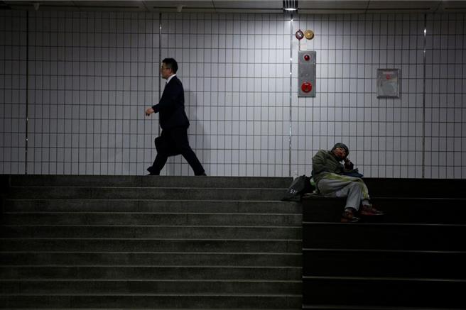 韓國首爾街頭，一名上班族路過街友身後（圖／路透社）