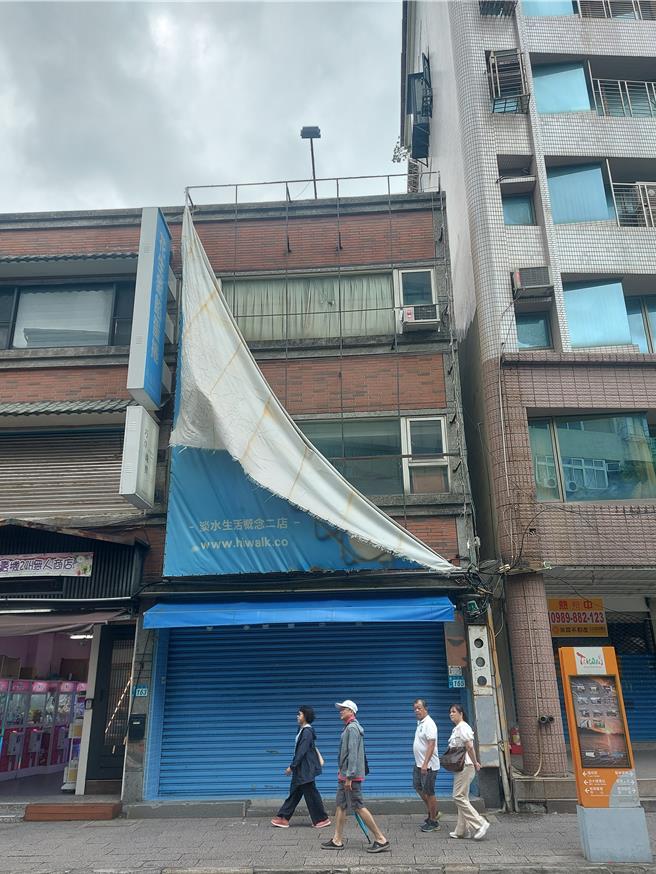 基北北桃2日停班停課，淡水沒有明顯風雨，午後遊客漸增，但老街上商家的廣告帆布破損，在風中吹拂。（張鎧乙攝）