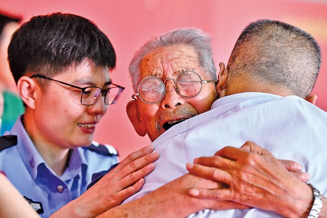 大陸公安部2021年6月啟動認親活動，90歲高齡的羅鳳坤（中）緊摟著被拐58年的兒子羅亞軍哭泣。（新華社）