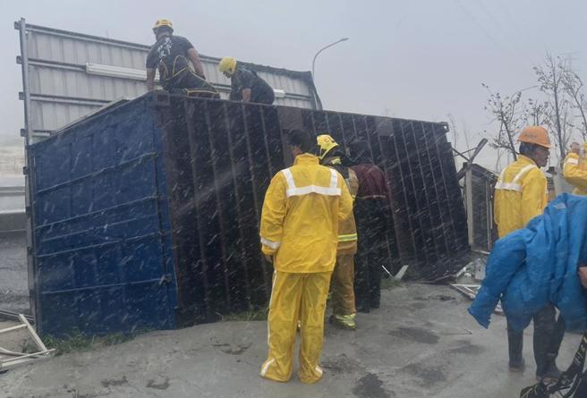 山陀儿强风暴雨下午致高市仁武区仁林路货柜屋翻覆，现场2名70岁老翁刚好在货柜屋内，警消赶到现场顺利将2人救出。（警消提供／林雅惠高雄传真）