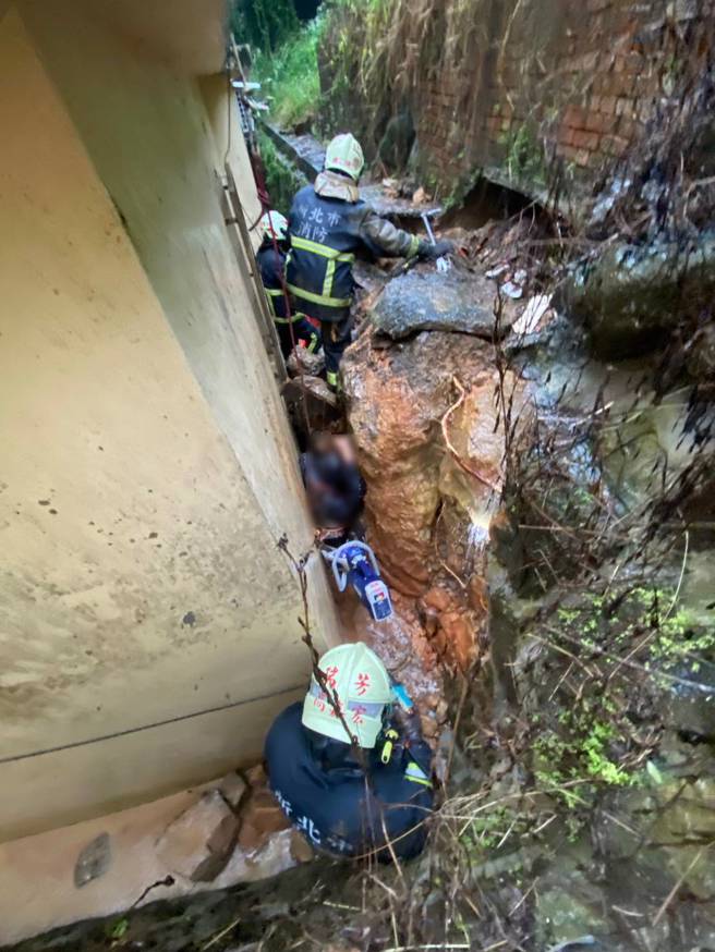 万里老翁因为住家后挡土墙崩落，导致脚部被夹住受困，消防队获报到场救援。（翻摄画面）