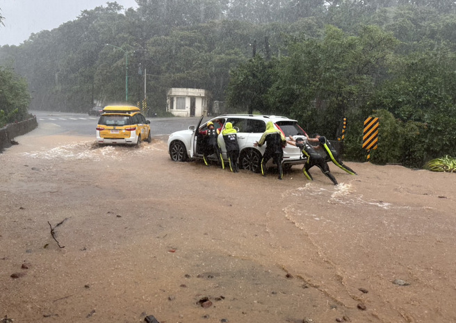 有女驾驶开车受困于新北金山名流路，警消以人力推车，将车辆推至积水较浅区域，协助女驾驶脱困。（图／新北市议员张锦豪提供）