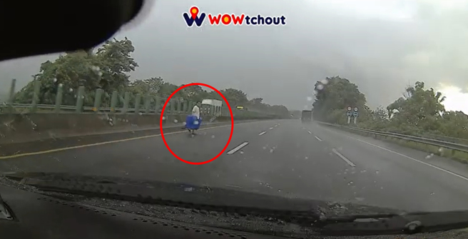 一名男子提著2個大箱子從左側竄出，準備穿越國道。（圖／翻攝自WoWtchout - 地圖型行車影像分享平台）