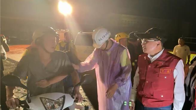 新北市长侯友宜（右）视察金山中角国小，遇见冒雨骑车来接学生的家长。（民眾提供）