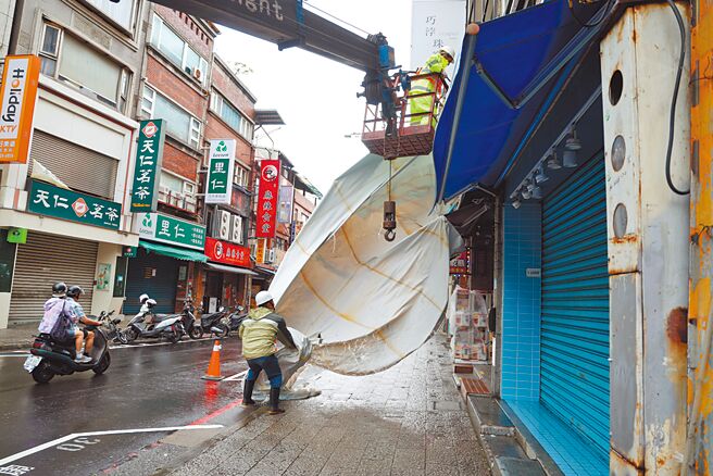 山陀儿颱风袭台，双北市连放2天颱风假，北部淡水有店家趁机拆除老旧的帆布广告。（邓博仁摄）