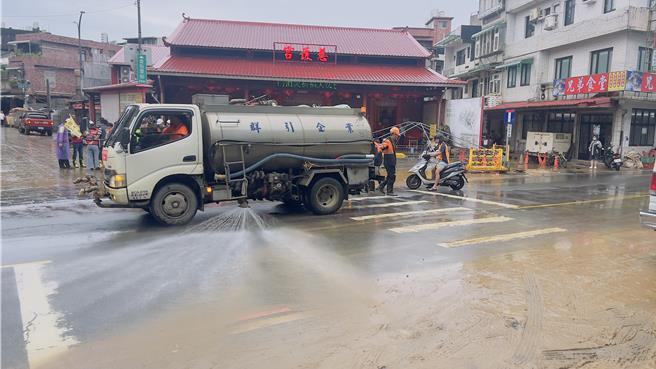 水车在路面洒水清除淤泥。（吕健豪摄）