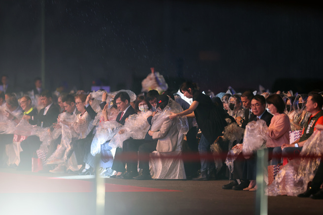 图为去年国庆晚会因突然下雨，蔡英文（图中戴黑色国旗帽者）临时穿上雨衣，冒雨欣赏表演。（读者提供／洪荣志台南传真）