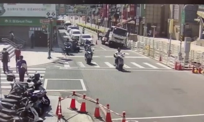 新莊中正路上施工，貨車到場吊掛水泥沙包，因重心不穩車輛翻覆，駕駛緊急跳開閃躲。（翻攝畫面）