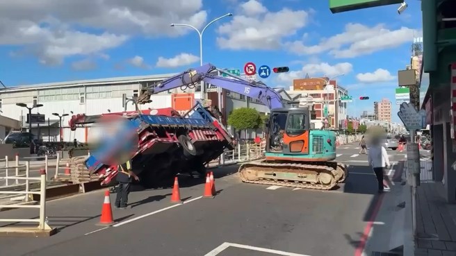 新莊中正路上施工，貨車到場吊掛水泥沙包，因重心不穩車輛翻覆，駕駛緊急跳開閃躲。（翻攝畫面）
