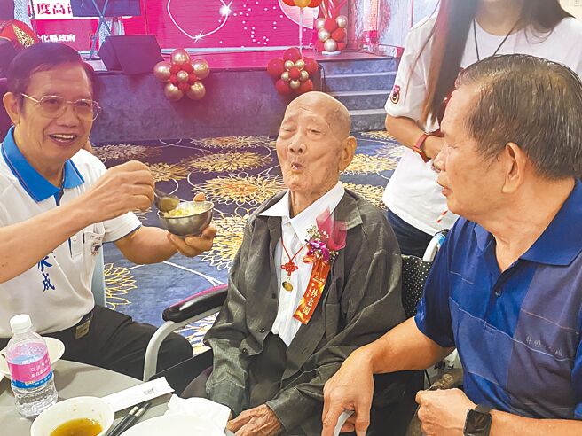 104岁人瑞林老闯（中）参加彰化高龄同学会，儿子林水成（左）表示，会把父亲爱吃的鱼肉弄碎拌在饭里，他一天能吃8碗饭。（叶静美摄）