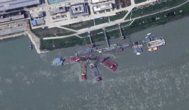 在武汉造船厂沉没的中共新式潜艇原被认为是核动力攻击潜艇，但最近五角大厦专家传出它是一艘核动力与常规混合动力潜艇。图为打捞沉没潜艇。（图／行星实验室卫星）