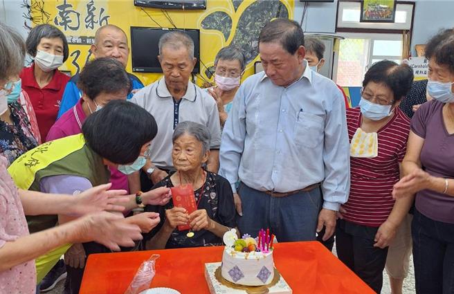 高雄市社會局人員送上1萬元重陽節禮金及百歲人瑞金鎖片1枚給李柯梗（圖中）時，她逗趣的說：「去年金鎖片送家人、今年一定要自己保管好」。（林雅惠攝）