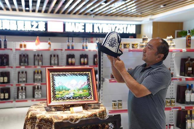 在新疆喀什跨境电商进出口商品展示交易中心，顾客在挑选吉尔吉斯出产的羊毛毡帽。（摘自新华社）