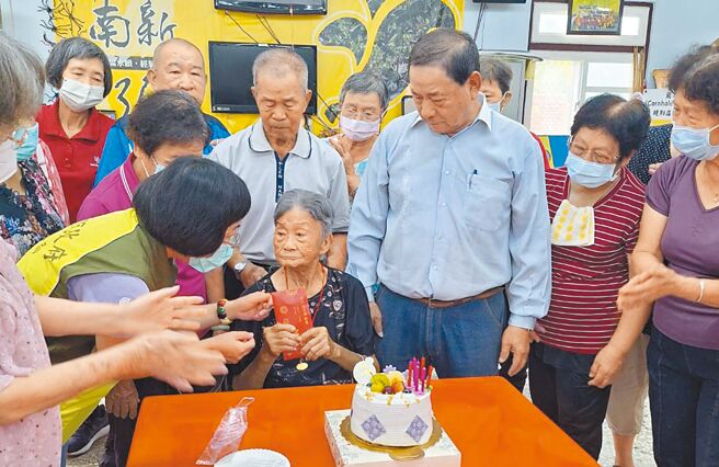 高雄市社會局人員為李柯梗（中）送上1萬元重陽節禮金及百歲人瑞金鎖片1枚。（林雅惠攝）