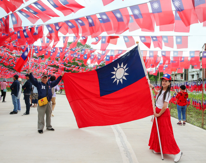 雙十國慶日將至，桃園市平鎮高齡84歲的國旗屋老闆張老旺，今年連續第30年自掏腰包舉辦國慶升旗典禮，受去年拔旗事件影響，今年移師龍岡圓環旁新落成公園舉辦，龍岡圓環現場還有復刻版的國軍與軍車，讓現場民眾排隊合照。（陳麒全攝）