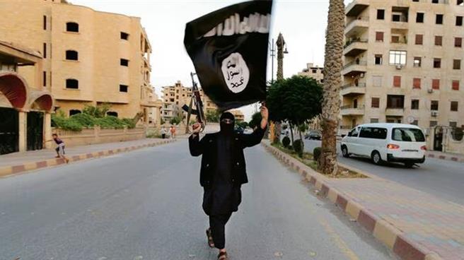 一名伊斯兰国成员在叙利亚北部城市拉卡挥舞组织旗帜。（路透社）