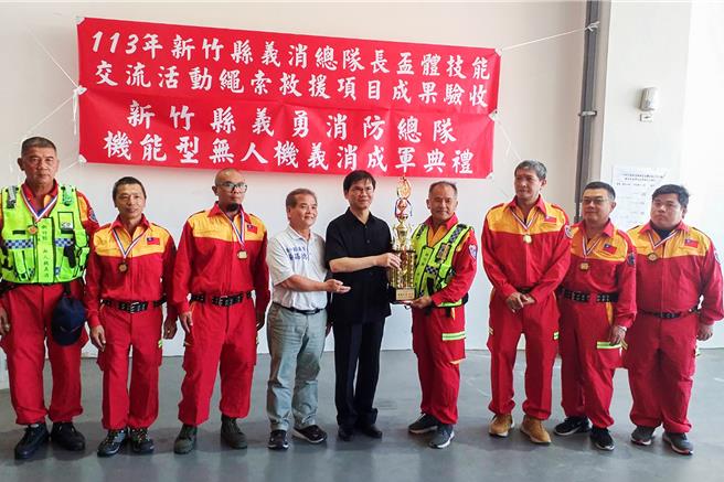 新竹縣義勇消防總隊12日成立機能型無人機義消，消防局長陳中振（中）頒發無人機義消展示成功獎盃。（新竹縣消防局提供／羅浚濱新竹傳真）