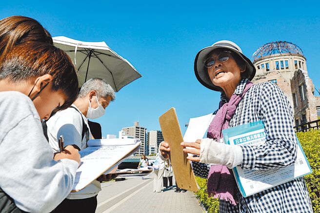 日本原子弹与氢弹受害者协会成员大内正子（音译）于广岛和平纪念公园邀请来访人员签署请愿书，呼吁政府早日批准禁止核武条约。（路透）