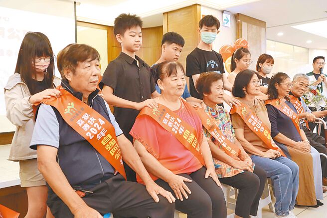 嘉義家扶中心13日舉辦自強阿公、阿嬤表揚，讓長輩享受一手帶大的孫兒及孫女捶肩、按摩、獻花與擁抱，長輩們臉上雖帶著笑，眼眶早已泛紅滿是淚水。（呂妍庭攝）