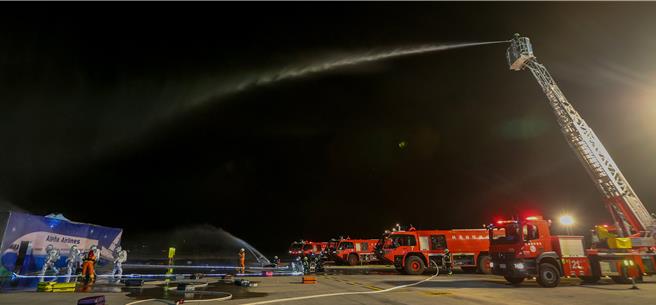 为进一步提升桃园国际机场在灾害抢救中的应变能力，桃园机场公司于16日晚间在第三航厦北侧的机坪举办了「113年度空难灾害防救演习」。此次演习旨在模拟夜间空难情境，共动员22个单位、超过60辆作业车辆及装备，并有200人次参与演习。（陈麒全摄）