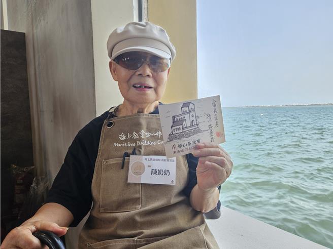 82岁的陈奶奶亲手绘制海上教堂咖啡纪念明信片，送给入场客人。（罗琦文摄）