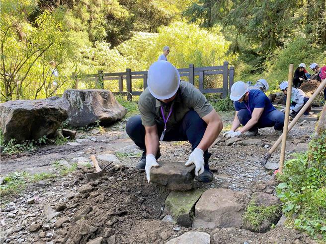 「特富野古道手作步道工作假期」参与伙伴以适合的石材进行步道铺设，来改善排水性。(林业署嘉义分署提供／吕妍庭嘉义传真)