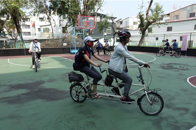 视障者由志工带领骑协力车，先在篮球场绕行试骑。（罗琦文摄）