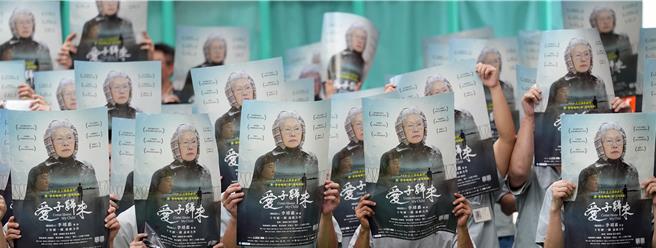 金獎導演李靖惠的最新紀錄片作品《愛子歸來》11月1日起將在全台戲院上映，22日在台北監獄安排電影首映會，邀請各公益團體代表與180位受刑人一同觀影。受刑人們在主辦單位的安排下，高舉電影海報合影。（黃世麒攝）