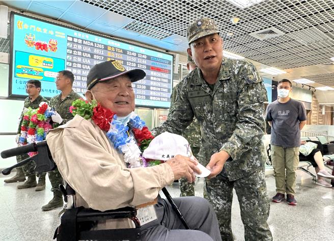 金防部指揮官李定中(右)親自到尚義機場出境大廳迎賓，一一為參戰官兵們戴上英雄牌、送上紀念帽，溫馨關懷每位老英雄的健康狀況。(于家麒攝)