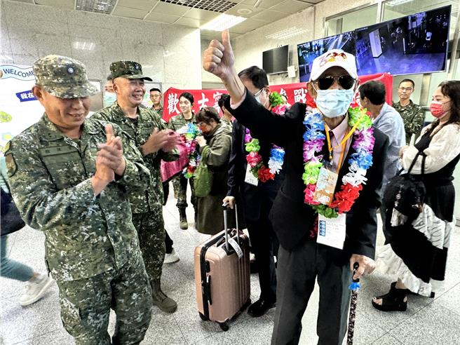 原本由家屬推著輪椅出關的98歲高齡老英雄梅錦義(右前)，見到金防部大陣仗的熱烈歡迎儀式，慷慨激昂的站起來向大家比讚致意。(于家麒攝)