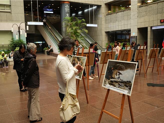 民眾佇足觀看照片。(黃敬文攝)