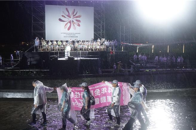 全民運動會昨晚在雨中開幕，選手踩水進場。（羅琦文攝）