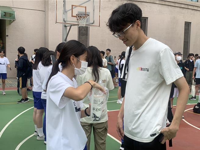 雄女同學歡喜接受雄中同學送的珍珠奶茶等飲料。（郭良傑攝）