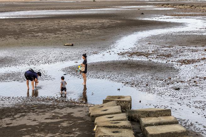 新豐鄉鳳坑沙灣沒有公廁和淋浴設施，民眾在退潮時到沙灘遊玩後，沒有地方能沖洗手、腳的沙子，只能在近岸積水處簡單潑水清洗。（羅浚濱攝）