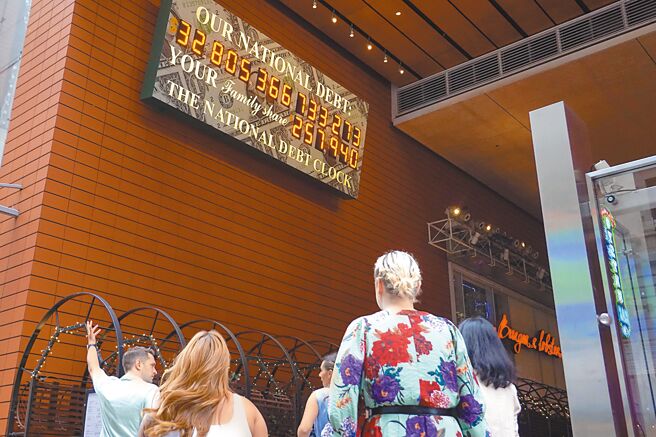 《日经》预测，全球政府债务余额到2024年底将超过100兆美元。图为纽约曼哈顿美国「国债钟」显示屏前的背影。（中新社）