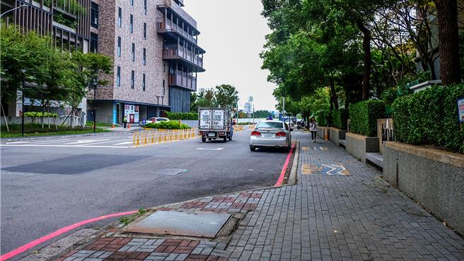 竹北远百（左边建物）开幕后，十兴国小周边道路行穿线走到家长接送区，易成危险马路动线，家长接送区常被违规停车，教育局办理「校园周边暨行车安全道路改善计画」工程30日动工，打造友善人本的通学廊道。（罗浚滨摄）