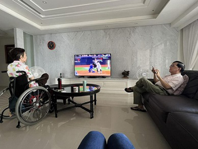 陈致中在脸书PO出一张照片，照片中吴淑珍坐在轮椅上聚精会神的看棒球世界大赛，阿扁则戴着老花眼镜在滑手机。(摘自陈致中脸书)